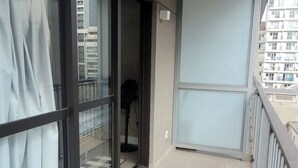 Un balcón con vistas a un paisaje urbano, un suelo a cuadros y una puerta que da a un espacio interior.