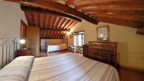Ein Schlafzimmer mit einem großen Bett, Holzbalken, einem Schminktisch und einem Spiegel.