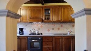 Eine Küche mit Holzschränken, einem eingebauten Backofen, einer Kaffeemaschine und einer gefliesten Spritzschutzwand.
