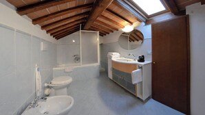 Ein Badezimmer mit Oberlicht, Badewanne, Toilette, Waschbecken und Spiegel.