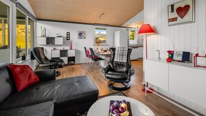 A modern living room with a black leather sofa, a dining area with a red lamp, and a kitchen in the background. - "Sjarlotte" - 400m to the fjord by Interhome (Skjern)