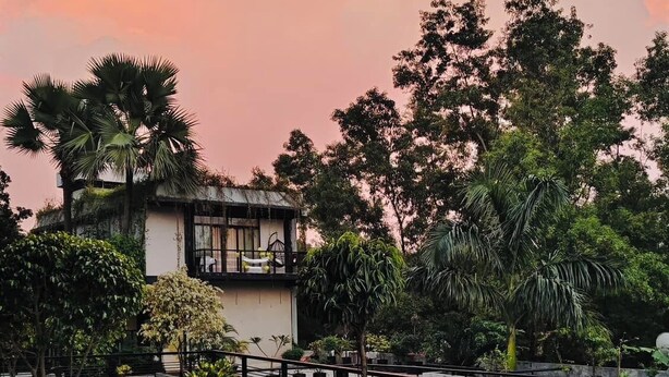 A rooftop pool with a view of trees and a building in the background. - Chuti Resort Purbachal (Ulukhola)