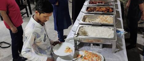 Ein reichhaltiges Buffet mit verschiedenen Speisen und Personal, das Gäste bedient.