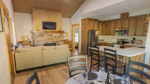 Une cuisine moderne avec des meubles en bois, une cheminée en pierre et un coin repas aménagé pour prendre un repas.