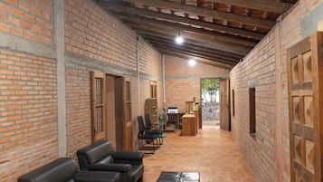 A brick-walled interior with a high ceiling, a reception desk, and seating area.