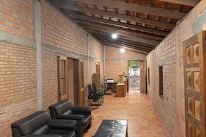 Interior con paredes de ladrillo, techo alto, mostrador de recepción y zona de estar.
