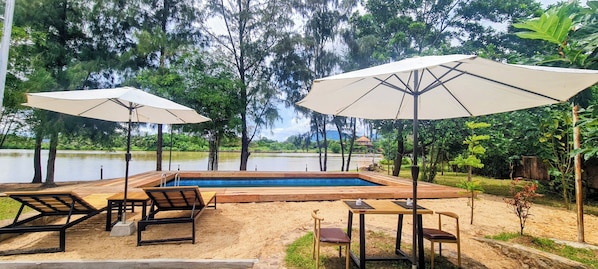 A poolside area with lounge chairs, umbrellas, and a wooden deck. - Sun&Roots Lodge Restaurant and Bar (Kampot)
