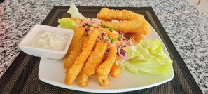 A plate with breaded and fried items, a salad, and a small bowl of sauce. - Sun&Roots Lodge Restaurant and Bar (Kampot)