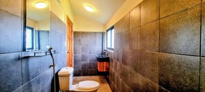 A compact bathroom with a toilet, sink, and shower area. - Sun&Roots Lodge Restaurant and Bar (Kampot)