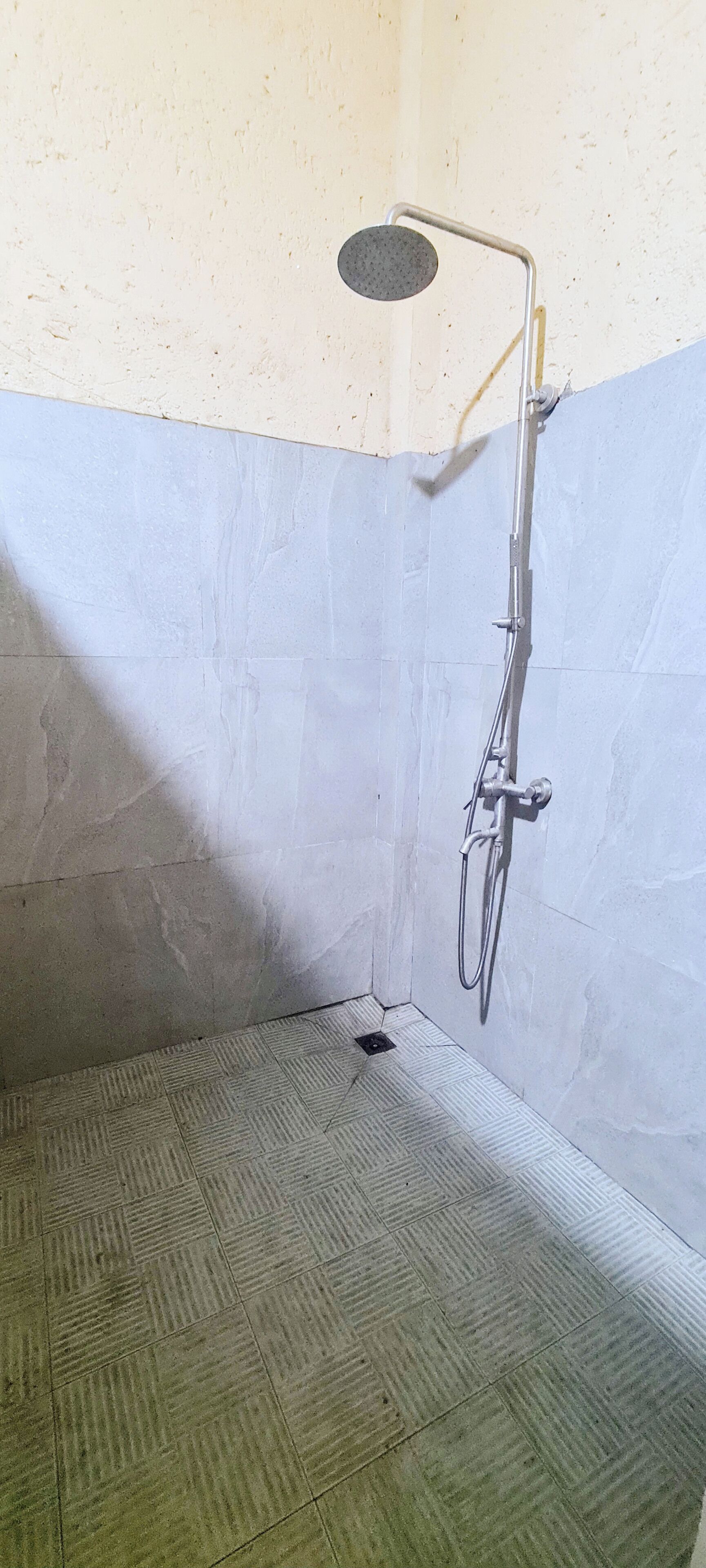 A shower area with a handheld showerhead, a floor drain, and tiled walls.