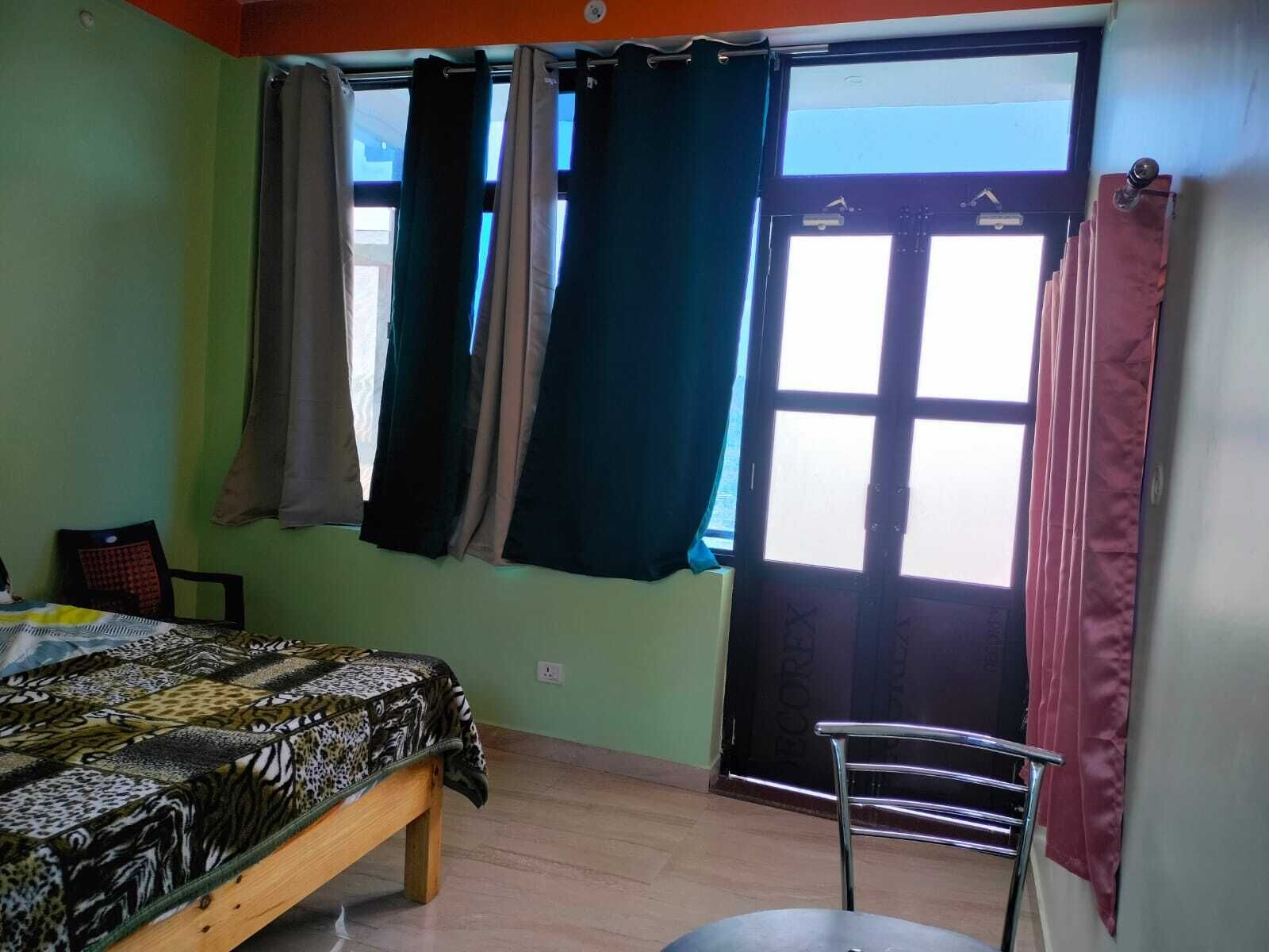 A room with a bed, a chair, and a window with curtains.