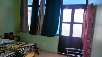 A room with a bed, a chair, and a window with curtains.