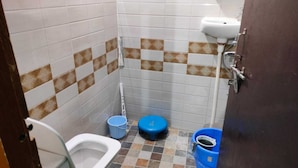 Een kleine betegelde badkamer met toilet, een hygiëneschuimer en een wastafel.