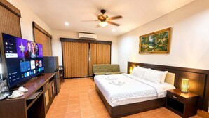 A hotel room with a bed, bedside table, TV, and a ceiling fan.