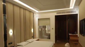 A modern hotel room with a large bed, bedside tables, a green rug, and a TV mounted on the wall. - Hotel Maharaja Crest (Katra)