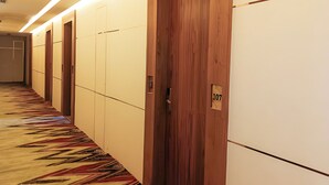 A hotel hallway with wooden doors, numbered 107, and a patterned carpet. - Hotel Maharaja Crest (Katra)