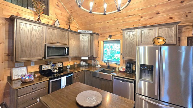 Cocina de cabaña de madera con una isla central, electrodomésticos de acero inoxidable y una araña.