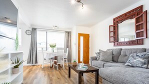 A modern living room with a grey sofa, a wooden coffee table, and a large mirror with a decorative frame. - Luxury Two-Bedroom Apartment (Upper Hutt)