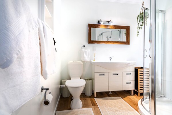 Une salle de bain moderne équipée de toilettes, d’un lavabo et d’une douche en verre.