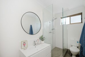 Een douche, handdoeken, zeep, toiletpapier