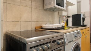 Een keuken met een fornuis, magnetron en wasmachine.