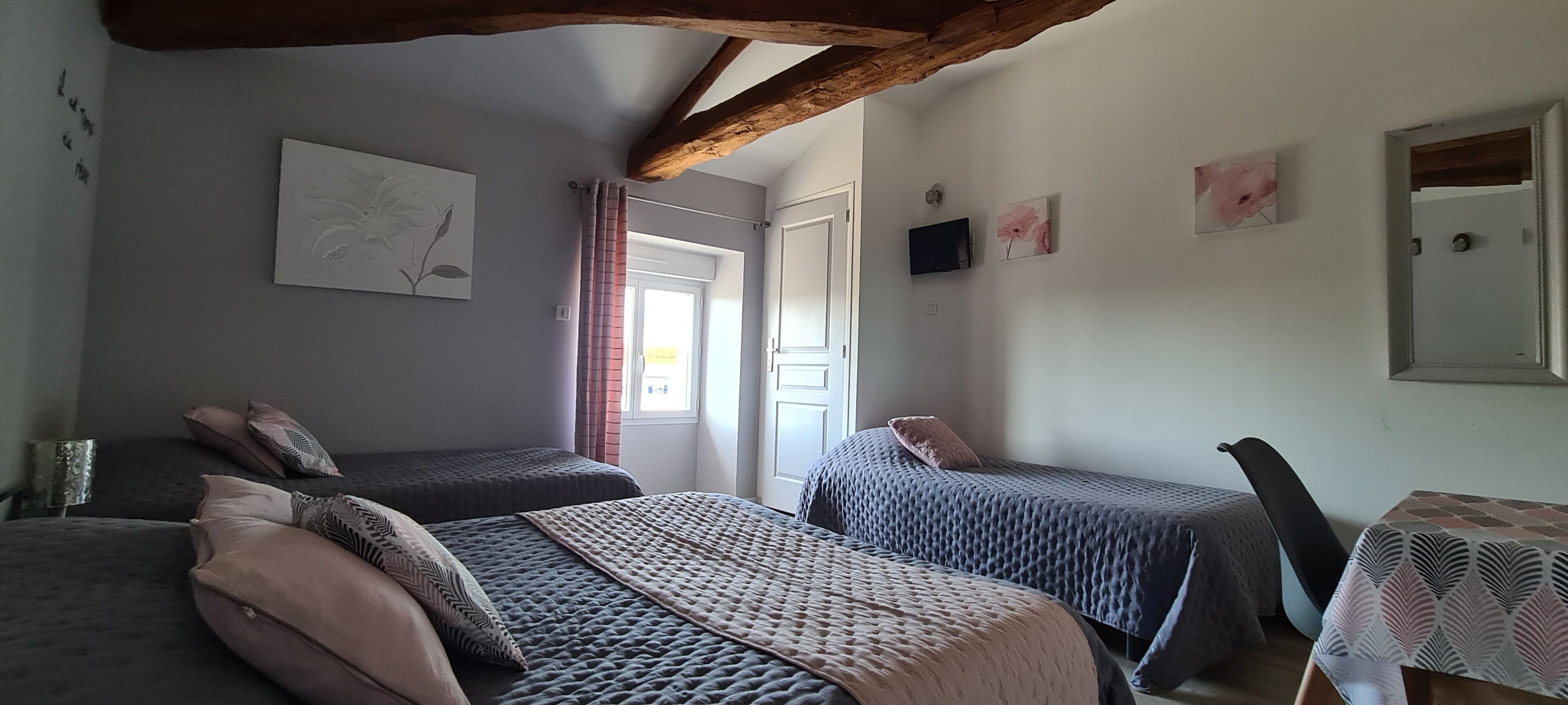 Ein Schlafzimmer mit zwei Betten, einem Tisch und einem Fernseher.