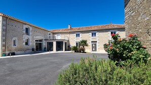 A two-story stone building with a tiled roof, a central entrance with glass doors, and a small balcony. - A la Gloriette Futuroscope (Neuville-de-Poitou)