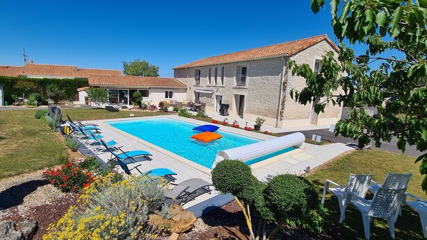 A swimming pool with lounge chairs, surrounded by well-maintained lawns and a stone building. - A la Gloriette Futuroscope (Neuville-de-Poitou)