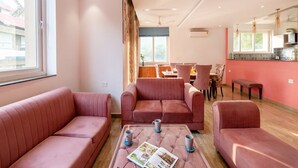 Una sala moderna con un conjunto de sofás, una mesa de centro con revistas, y un comedor con sillas y una mesa.