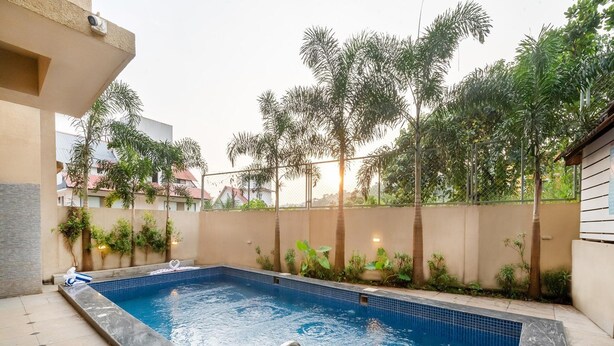 Una piscina con jacuzzi integrado, rodeada de follaje y una valla.