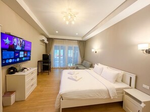 Una camera d'albergo con un letto grande, una televisione, una scrivania e una sedia.