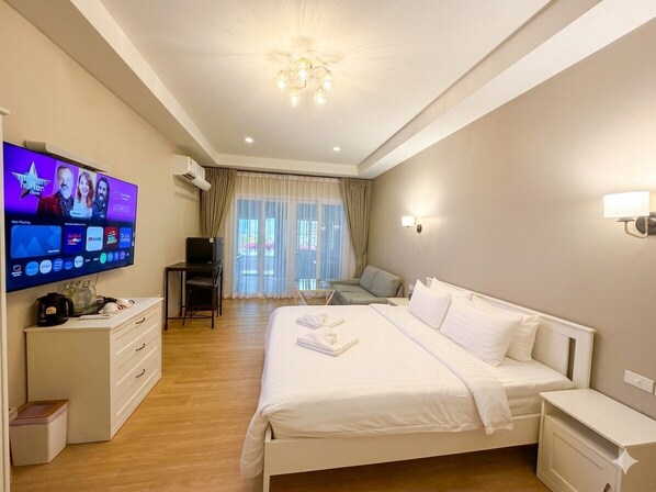 Una habitación de hotel con una cama grande, televisión, escritorio y una silla.