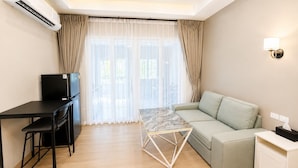 A modern living room with a sofa, a dining table, and a TV. - Large Studio with Kitchen – 50m from Jomtien Beach (Muang Pattaya)