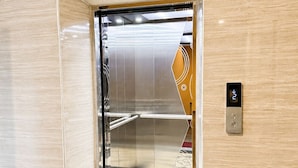An elevator with a metallic interior, a red mat at the entrance, and a wall-mounted control panel. - Large Studio with Kitchen – 50m from Jomtien Beach (Muang Pattaya)