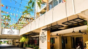 A hotel entrance with a sign, outdoor seating, and a balcony with string lights. - Large Studio with Kitchen – 50m from Jomtien Beach (Muang Pattaya)