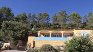 A yellow building with a tiled roof, a gated entrance, and a balcony.