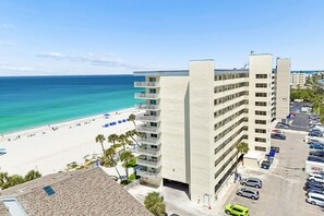 A hotel with a beach view, multiple floors, and a parking lot.