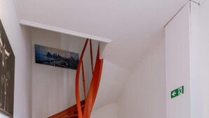 Een wenteltrap met oranje leuningen die naar een verdieping leidt.