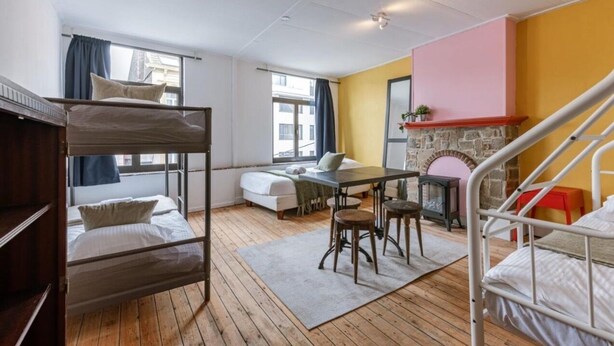 A dormitory room with bunk beds, a small table with stools, a fireplace, and a window with curtains. - Delightful 4-bedroom apartment in Gent (Gent)