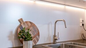 A modern kitchen with a stainless steel sink, a wooden cutting board, and a potted plant. - Delightful 4-bedroom apartment in Gent (Gent)
