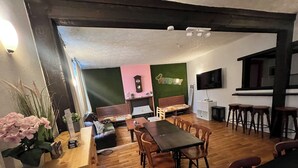 Een eetgedeelte met een houten tafel en stoelen, een bank en een bar met krukken.