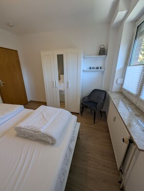 A bedroom with a bed, a wardrobe, a chair, and a radiator. - Comfortable vacation rental near the beach at Nige Ooge 9 with a balcony - House Nige Ooge (Cuxhaven)