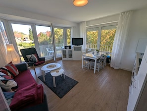 A spacious living area with a sofa, a dining table, and a TV.