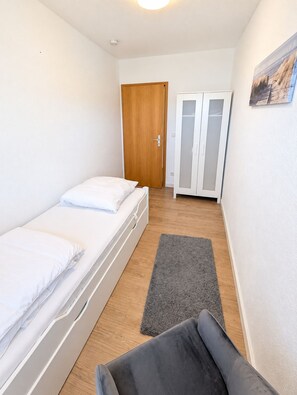 Une petite pièce propre, avec un lit, une armoire et une porte.