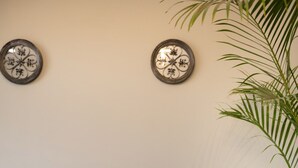 A grey sofa with two white pillows, a small round wooden table with a vase, and a large green plant. - Degla by Spacey (#37) |1BR in Maadi (Cairo)