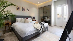 A modern bedroom with a large bed, a potted plant, and artwork on the wall. - Degla by Spacey (#37) |1BR in Maadi (Cairo)