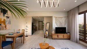 A modern living room with a dining area, a TV, and a large window with curtains. - Degla by Spacey (#37) |1BR in Maadi (Cairo)