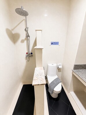 Ein modernes Badezimmer mit Dusche, Toilette und einem Marmorwaschtisch.