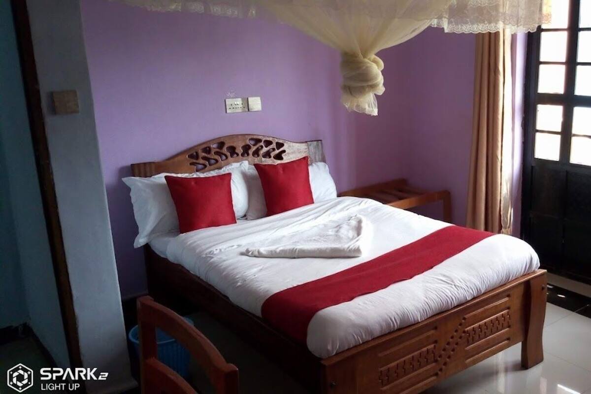 A neatly made bed with a wooden headboard, a red and white bedspread, and a canopy.