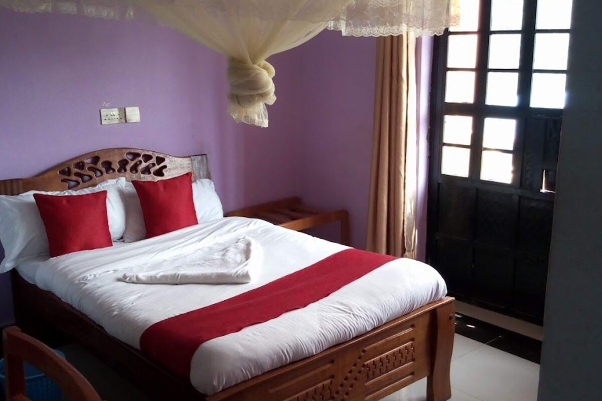 A neatly made bed with a wooden headboard, a red and white bedspread, and a canopy.